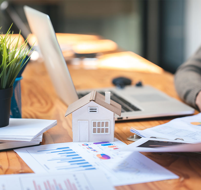gestor-realizando-estudo-de-demanda-imobiliaria-analisando-graficos-ao-lado-de-modelo-de-casa