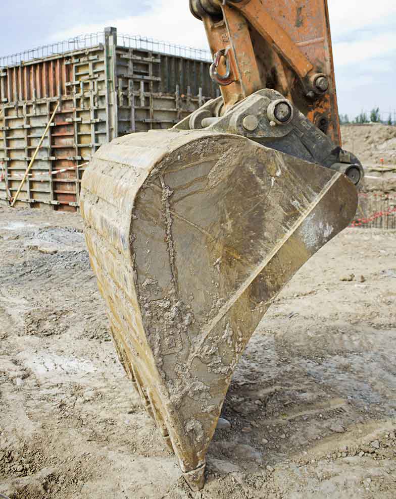 concha de uma escavadeira pesada apoiada no solo em um canteiro de obras ilustrando grandes projetos de infraestrutura no processo de desapropriacao por utilidade publica