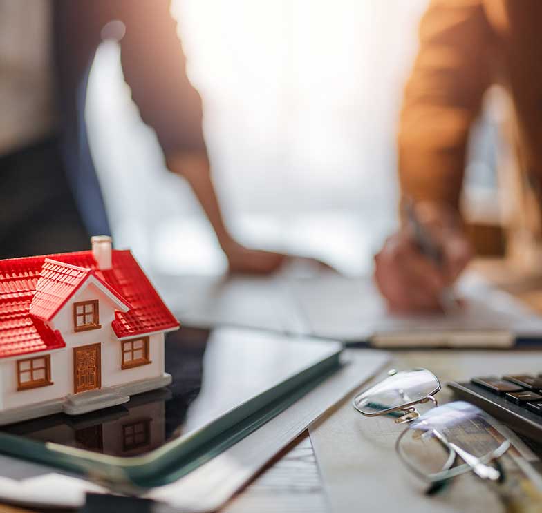 mesa executiva com maquetes de prédios e calculadora sugerindo como declarar desapropriação no imposto de renda com base em avaliação técnica de ativos.